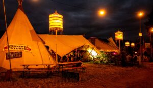 25ft diameter Tipi joined to 30ft diameter Yurt with canvas awning as the Ancient Futures venue in Glastonbury Festival Tipi Field at night