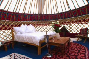 Luxury Yurt inetrior witgh double bed and decorative Kyrgyz felt rugs and wall hangings