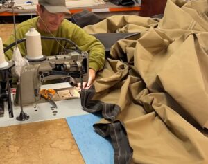 sewing machinist making a Tipi, passing the heavy canvas through the machine